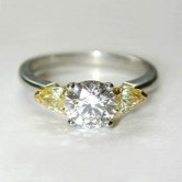 Platinum ring set with a round brilliant cut diamond and 2 pear cut natural fancy yellow diamonds